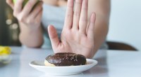 Female-Pushing-Away-A-Chocolate-Frosted-Donut-As-Part-Of-Her-Low-Carb-Diet