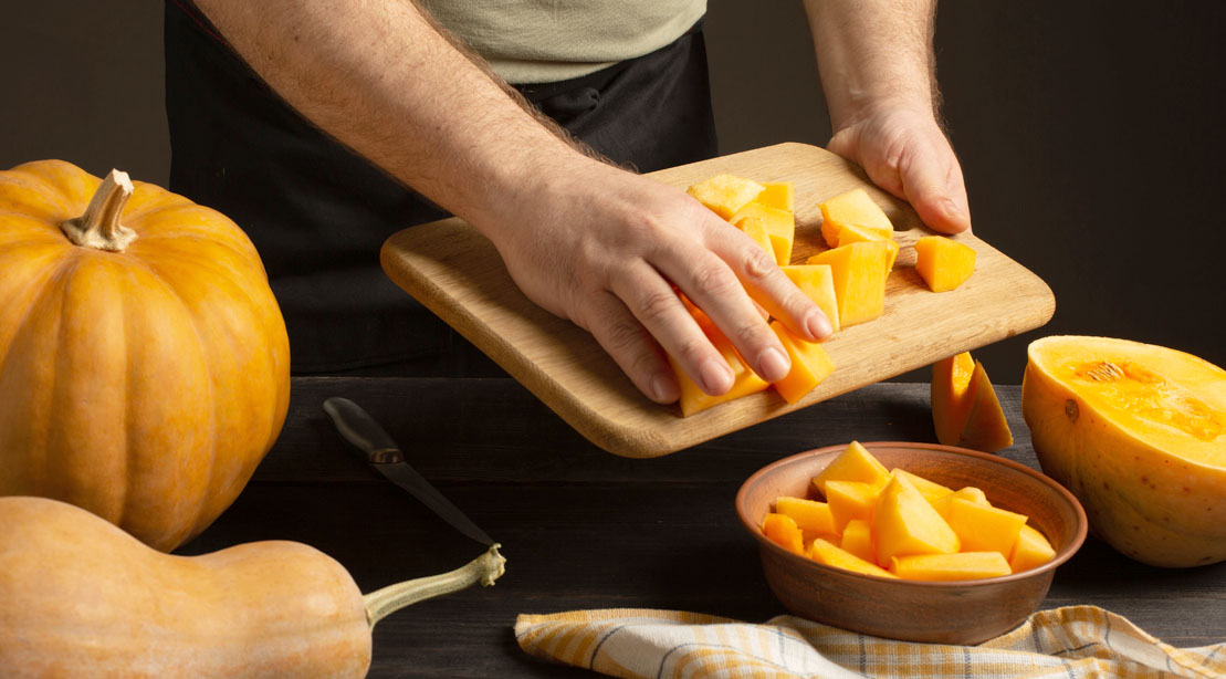 A muscular man bulking up with pumpkins and meal prepping with pumpkins