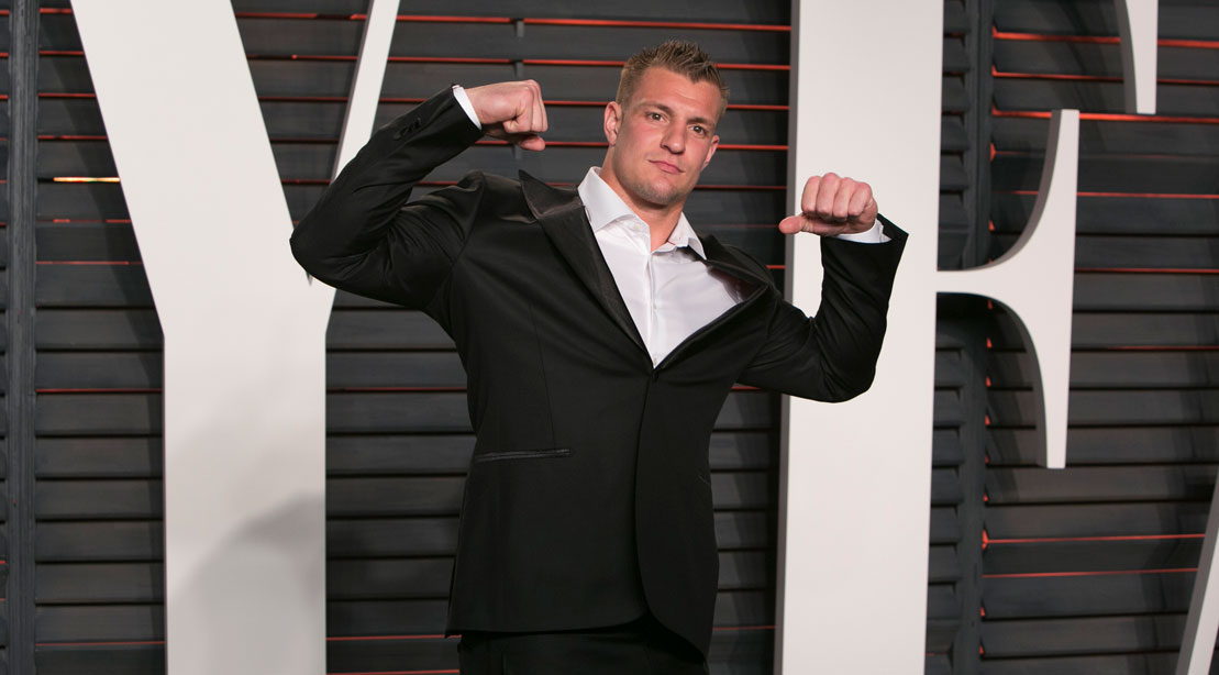 Rob Gronkowski flexing his arms in a black suit