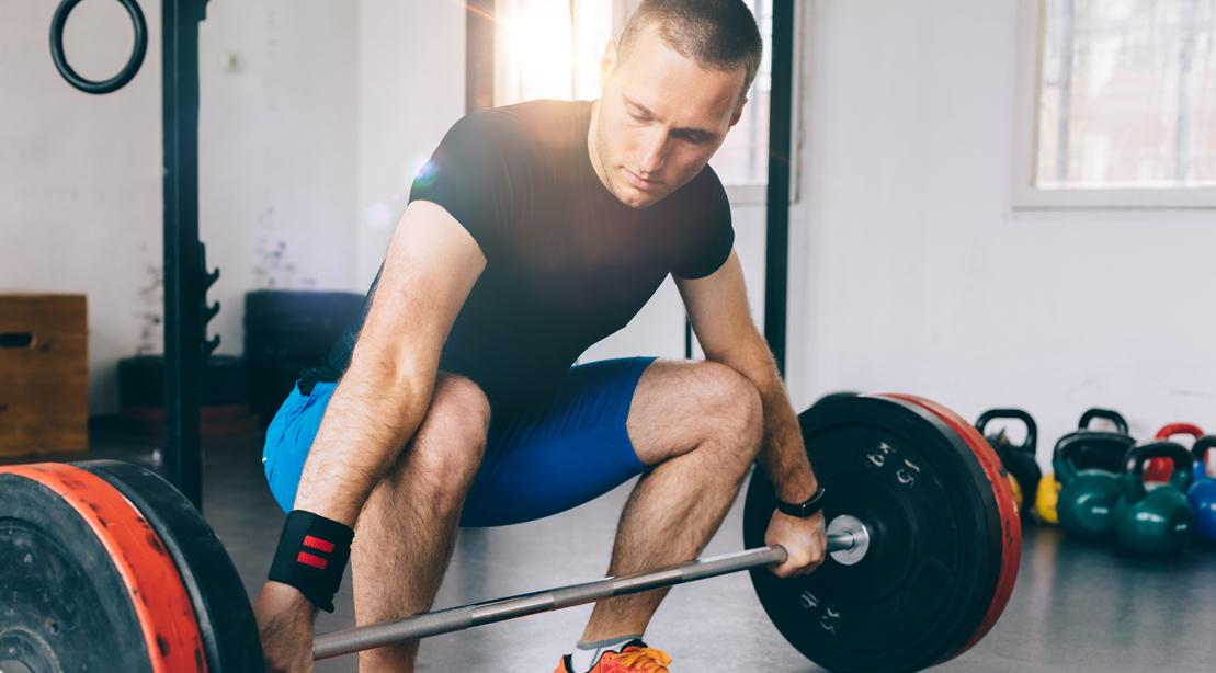Fit man making deadlifting adjustments to his Barbell Deadlift form so that he can lift more