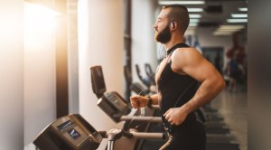 Man with muscular arms working out his cardio by running on a treadmill in the gym