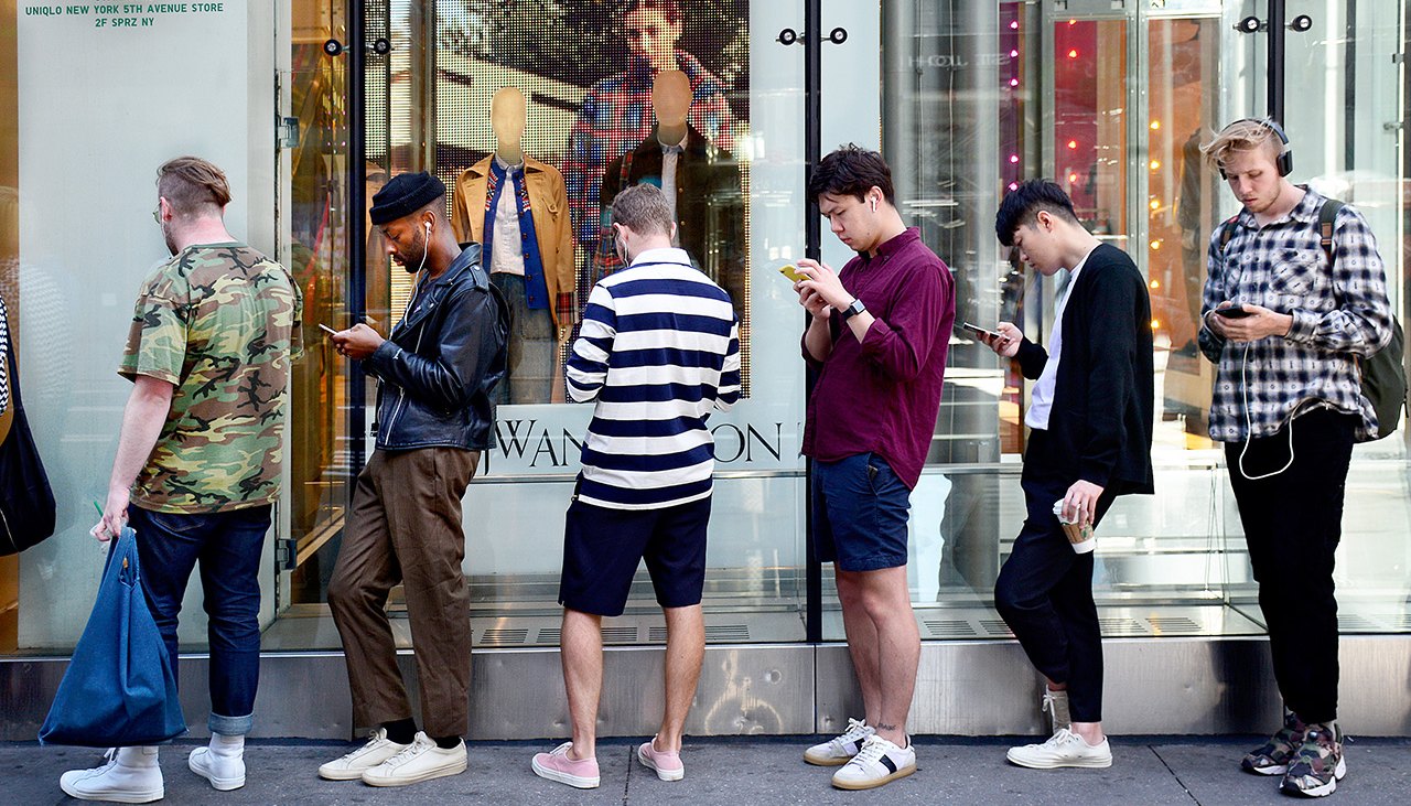 Men Using Smart Phones While Standing in Line
