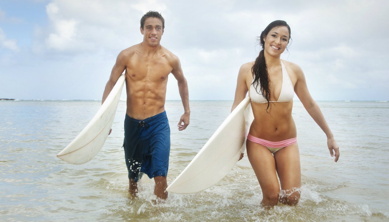 Couple carrying surfboards in the ocean