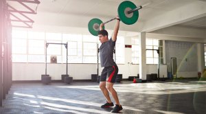 Fit Man in the gym performing a barbell clean and Push Press exercise