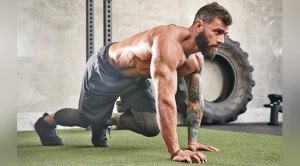 Muscular fit man with beard performing a bodyweight cardio exercise the bear crawl exercise