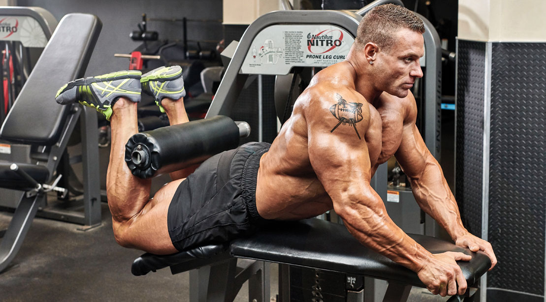 Bodybuilder doing workouts for legs with reverse leg curl exercise