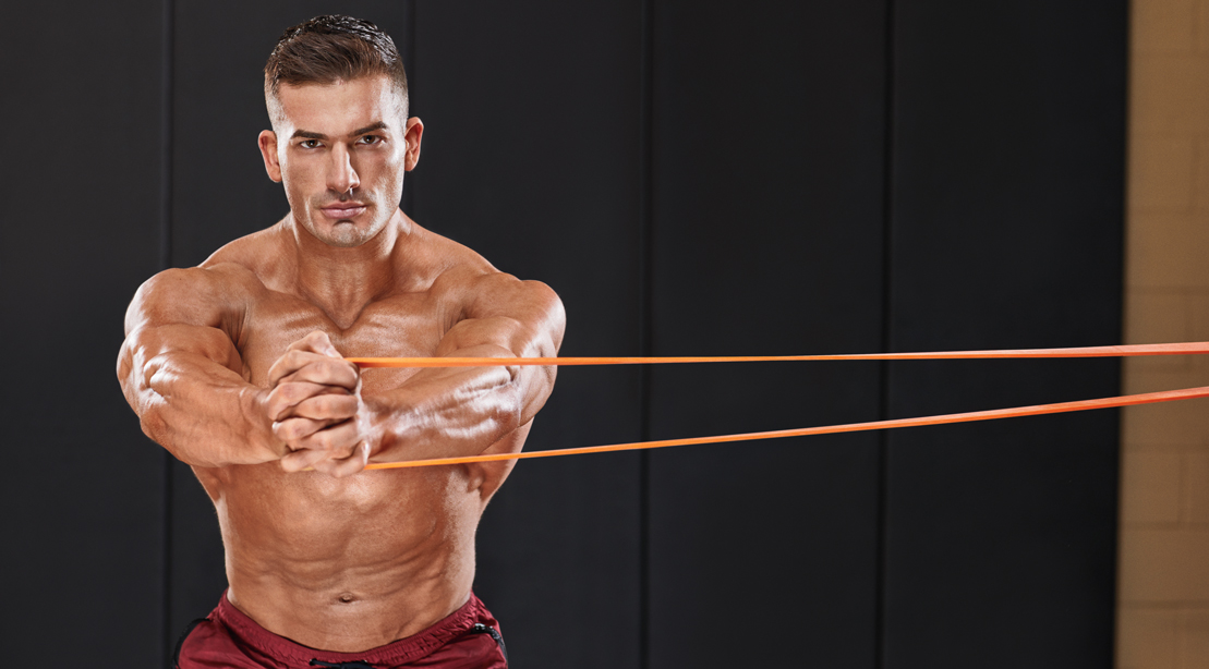 Muscular bodybuilder with his shirt off performing a pallof press exercise in his resistance band workouts routine
