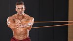Muscular bodybuilder with his shirt off performing a pallof press exercise in his resistance band workouts routine