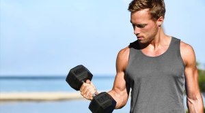 Fitness model doing outdoor workouts with a dumbbell bicep curl exercise for bigger biceps