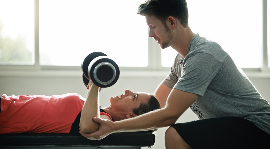 Trainer Helping Woman Lift Weights