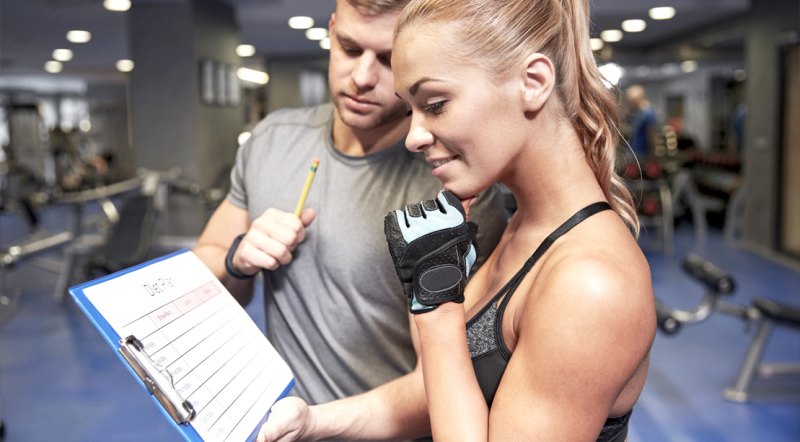 Female fitness enthusiast looking over her personal trainer training chart to build muscle