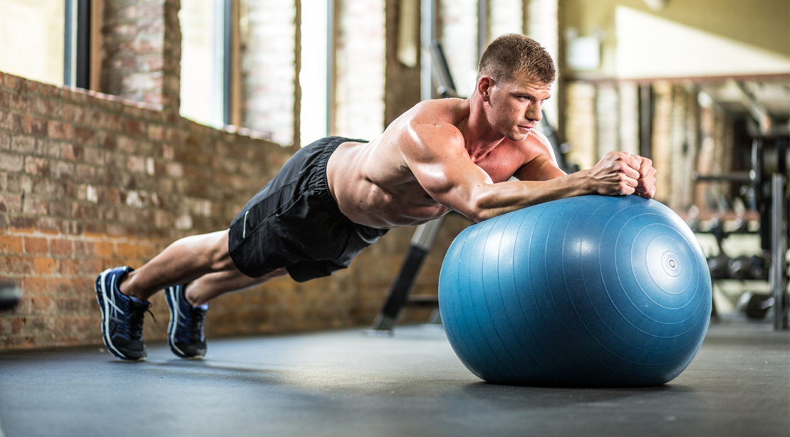 Fit man performing a stability ball exercises at the gym