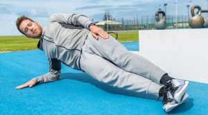 Fit man working out door doing a side plank exercise
