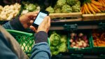 Man shopping in supermarket and using smartphone