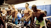 Bodybuilders in a bodybuilding competition lifting dumbbells in front of a mirro