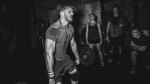 A black and white image of a Crossfitter deadlifting while sweating and exercising for power and explosiveness