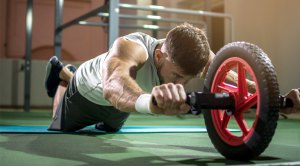 Man working out with an ab wheel rollout exercise in the gym