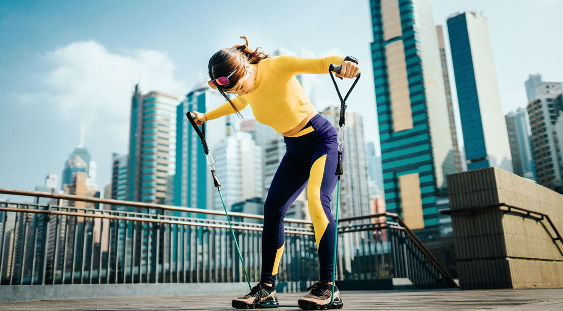 Woman in an urban area working out with resistance bands 