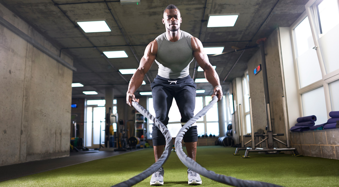 Man Working Out With Battle Ropes in Gym