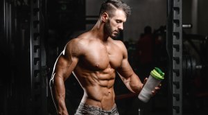 Bodybuilder looking at a shaker filled with a protein shake