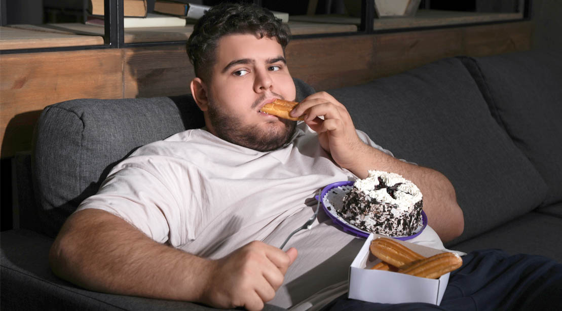 Fat Man With Bad Eating Habits In A Reclyiner Overeating On Sweets