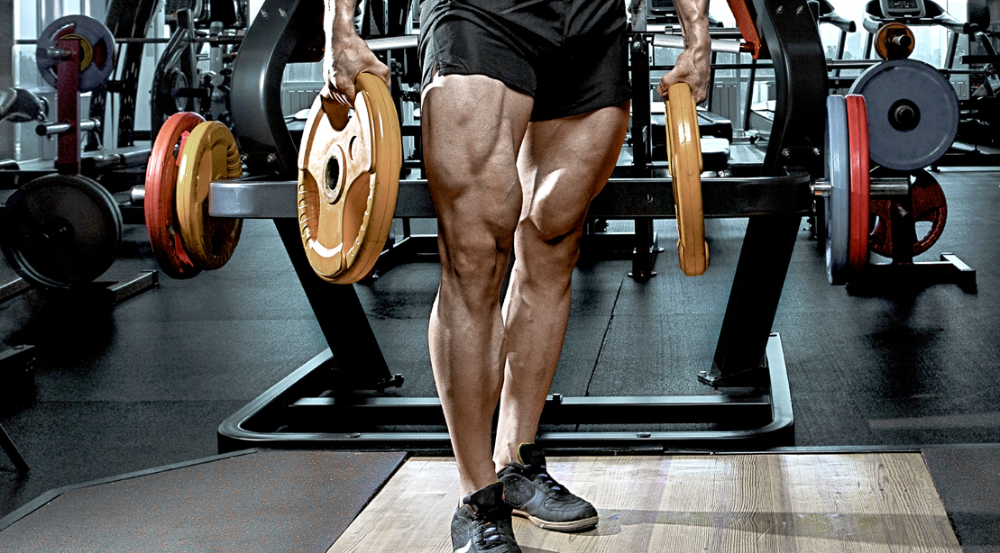 Bodybuilder holding barbell plates and showing off his quads