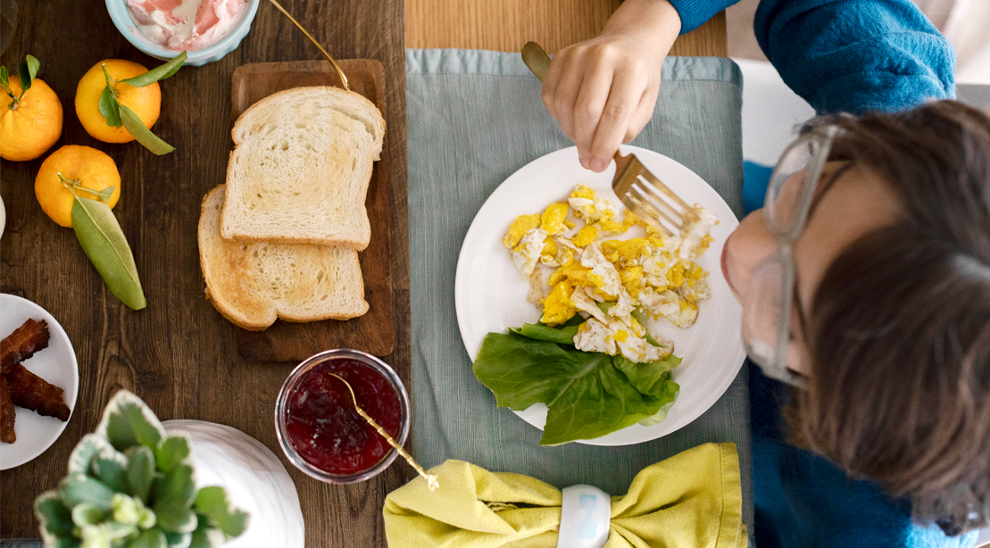 Person-Eating-Scrambled-Eggs-on-Plate