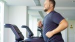Overweight man running on a treadmill in an empty gym