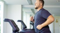 Overweight man running on a treadmill in an empty gym fixing his bad habits