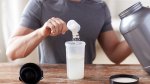 Muscular fit man adding whey protein powder into a shaker