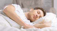 رجل ينام بهدوء في سرير بملاءات بيضاء.
