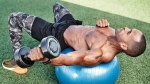 Man doing swiss ball bicep curl while working out outdoors