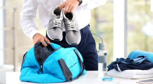 Business man packing gym bag with sneakers