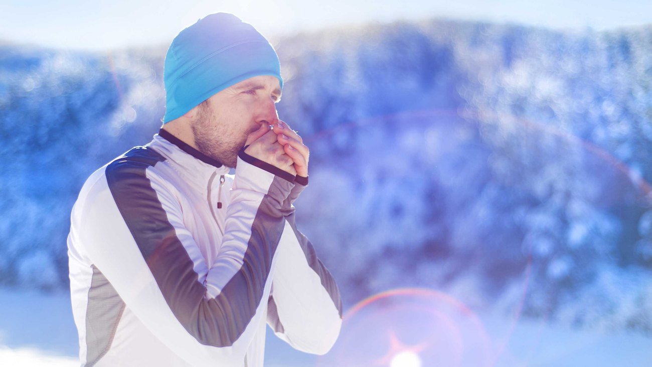 Fit male warming his hands while winter running