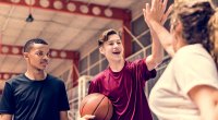 Two Teenage Boys Playing Basketball High Fiving Female Coach