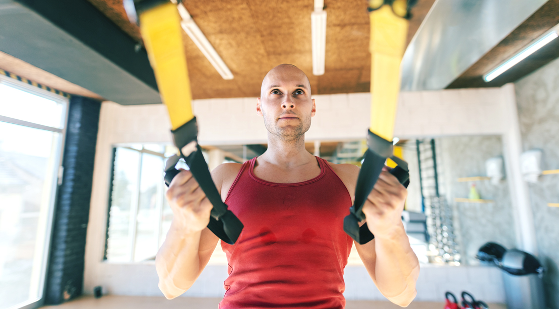 Focused-Bald-Man-Doing-TRX-Recline-Row and TRX accessory exercises for his suspension trainer exercises