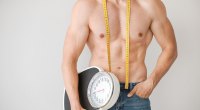 Muscular Male Holding Scale Measuring Tape Around Neck