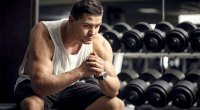 Male-Bodybuilder-In-Front-of-Dumbbell-Rack-Thinking-about how he can keep his resolutions.