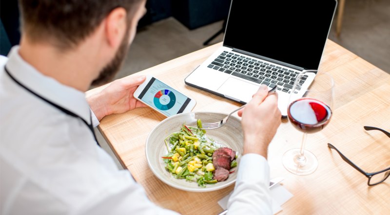 Man eating a salad at while at work and counting his calories and tracking his macros