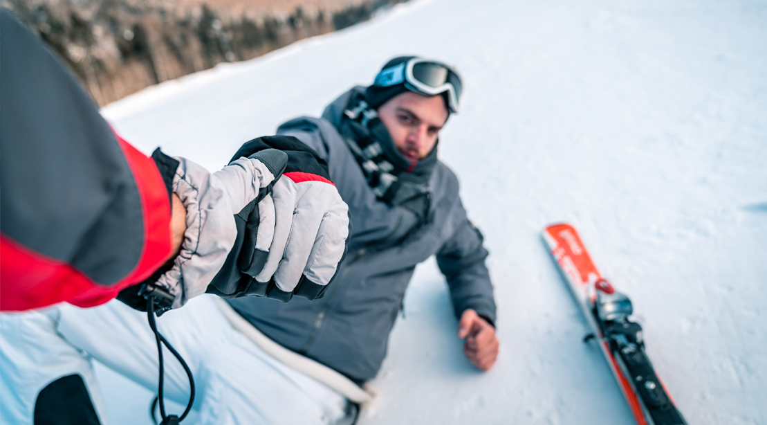 Skiier-Being-Helped-Back-Up-Fallen-Snow-Helping-Hand