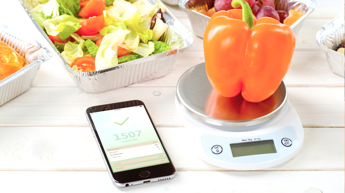 Iphone-Calorie-Counting-App-Sorrounded-By-Vegetables-And-Orange-Pepper-On-Food-Scale