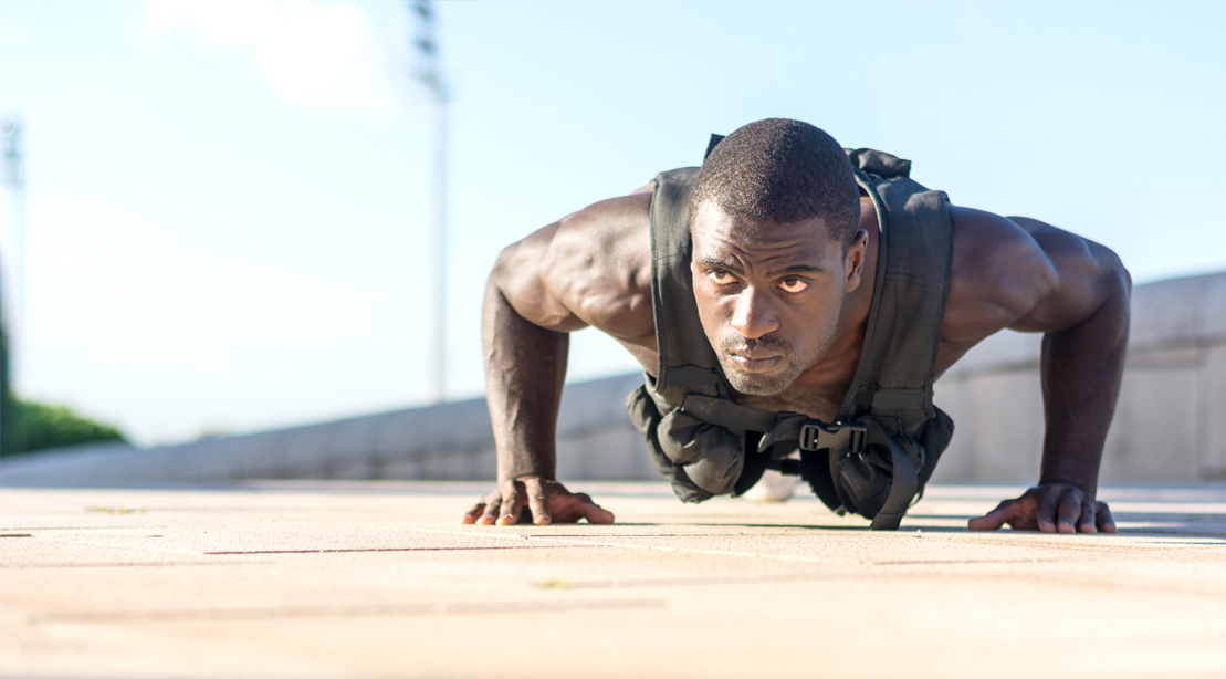 Fit man performing a bodyweight training plan using a weighted vest pushup
