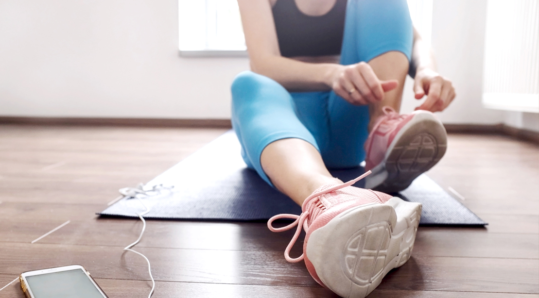 Fit-Female-In-Fitness-Clothes-Tying-Sneakers-At-Home
