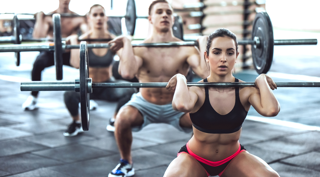 Group of fit people attending a group fitness class performing a light weight front squat