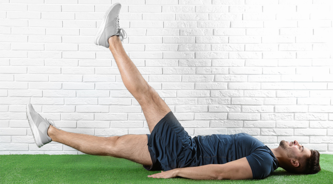 Happy man doing bodyweight exercise called the flutter kick exercise