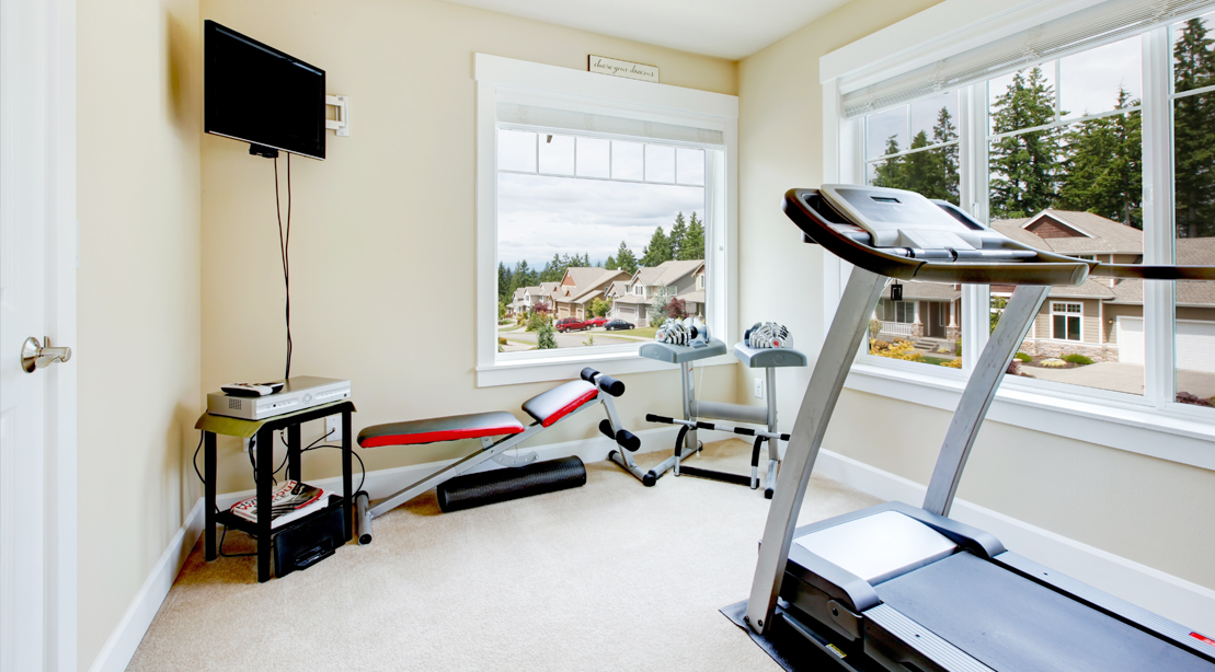 Home-Gym-Room-Filled-With-Exercise-Equipment-Overlooking-Suburbia