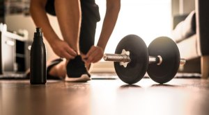 Person tying sneakers before performing an at home workout with dumbbells
