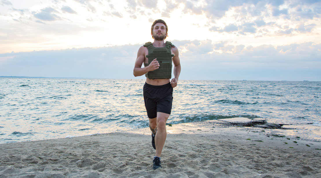 Man running on the beach while wearing a weighted vest