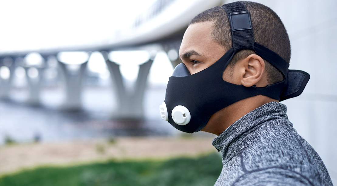 Fit man training outdoors while wearing a high altitude training mask