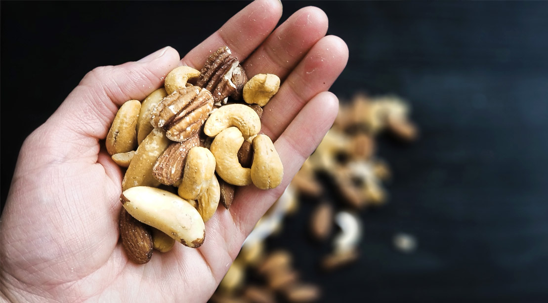 A variety of nuts in the palm of a hand.